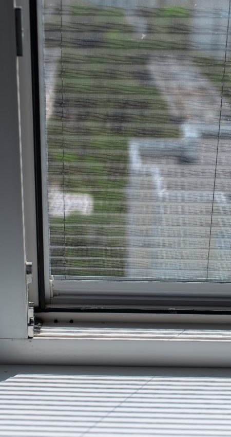 Close-up of plastic window with modern mosquito net. Sunny day.